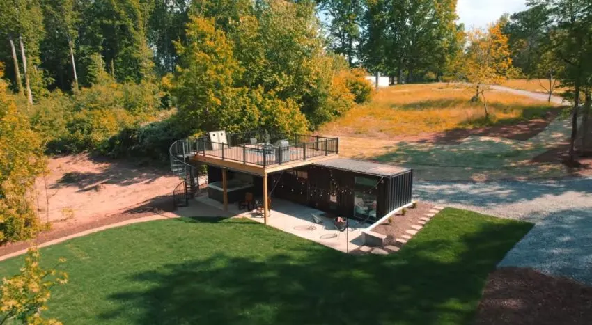 Shipping container with engineered rooftop deck and railings